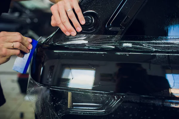 Les mains du travailleur installe film de protection de peinture de voiture enveloppement . — Photo