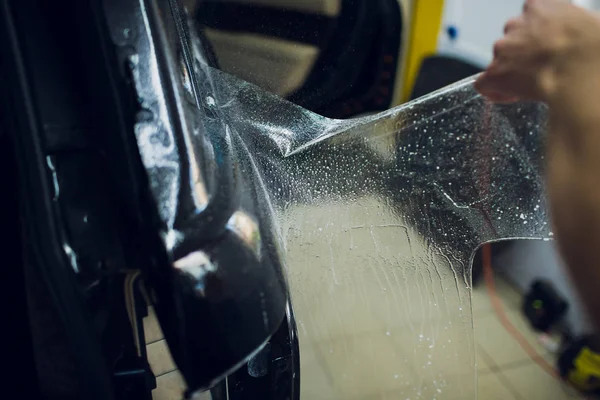 Työntekijän kädet asentaa auton maali suojakalvo kääri . — kuvapankkivalokuva