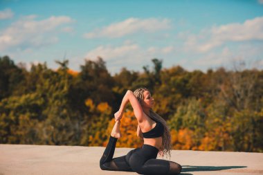 Büyük şehirde bir gökdelenin çatı üzerinde yoga yaparken kadın.