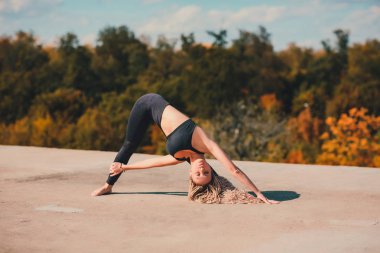 Büyük şehirde bir gökdelenin çatı üzerinde yoga yaparken kadın.