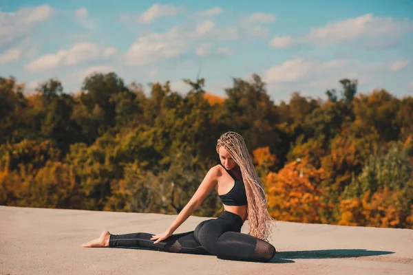 Femme faisant du yoga sur le toit d'un gratte-ciel dans une grande ville . — Photo