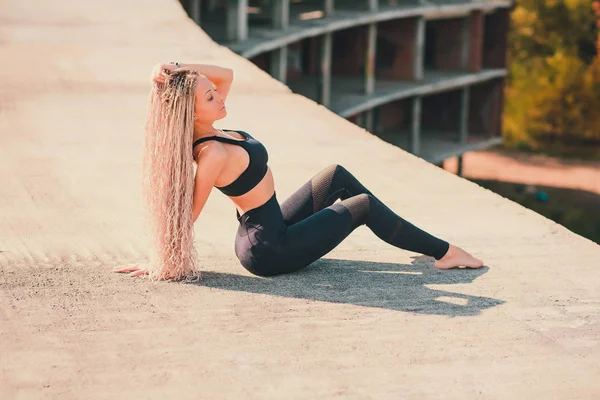 Woman doing yoga on the roof of a skyscraper in big city. — Stock Photo, Image