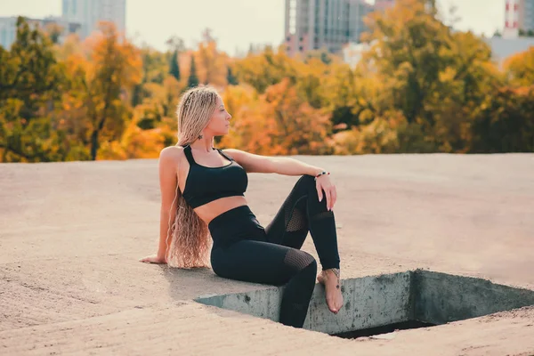 Femme faisant du yoga sur le toit d'un gratte-ciel dans une grande ville . — Photo