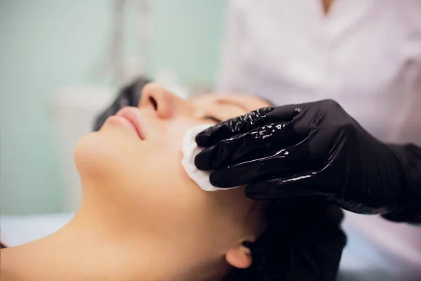 Limpie con cara de servilleta estéril. Mujer joven recibiendo tratamientos en salones de belleza . — Foto de Stock