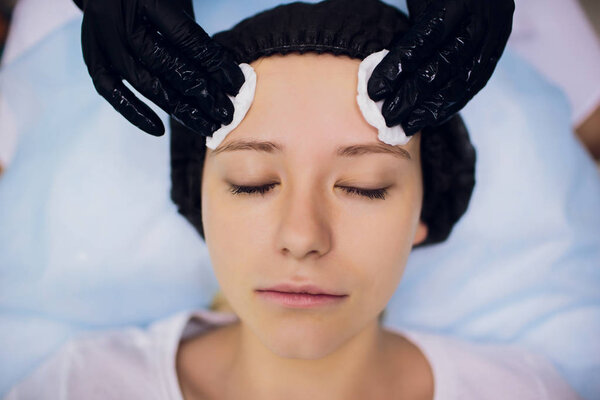 Вытирать стерильной салфеткой. Молодая женщина получает процедуры в салонах красоты
.