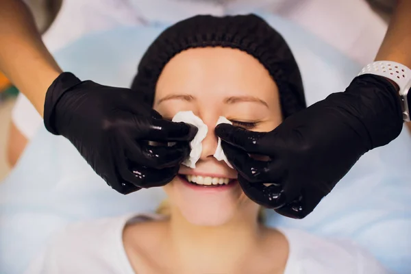 Wipe with sterile napkin face. Young woman receiving treatments in beauty salons. — Stock Photo, Image