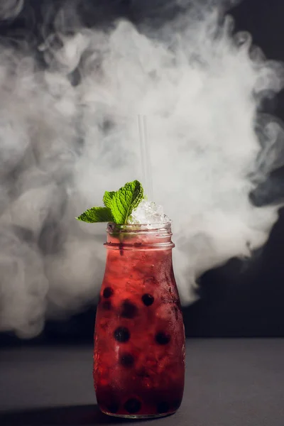 Темный и бурный коктейль из рома с клубникой на фоне дыма . — стоковое фото