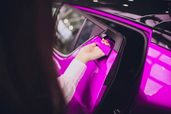 Mano femenina para insertar la puerta trasera de color rosa coche abierto. para el transporte y la imagen del automóvil — Foto de Stock