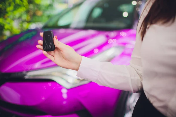Feminino segurando chaves do carro com carro no fundo cor-de-rosa — Fotografia de Stock