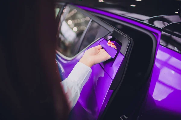 Mano femenina para insertar la puerta trasera de color púrpura coche abierto. para el transporte y la imagen del automóvil — Foto de Stock