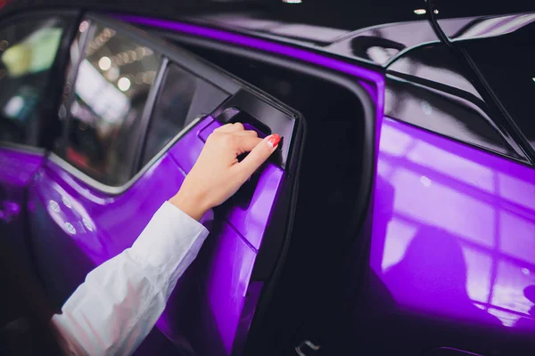 Mão feminina para inserir a porta traseira carro aberto cor roxa. para transporte e imagem automotiva — Fotografia de Stock