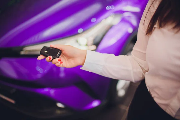 Frau hält Autoschlüssel mit Auto auf Hintergrund lila Farbe — Stockfoto