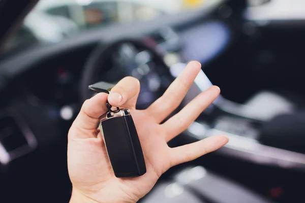 Man hand with car key on background salon new auto