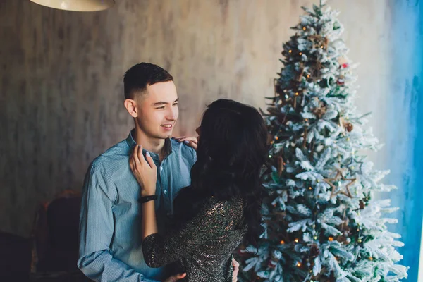 Un hombre y una mujer están bailando sobre el fondo de un árbol de Navidad. Hermosa familia joven feliz celebrando la Navidad juntos. Los amantes del Año Nuevo juntos en un apartamento en el estilo Loft —  Fotos de Stock