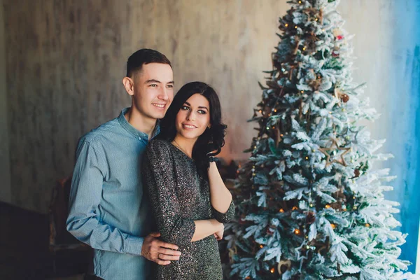 Muž a žena se tančí na pozadí vánoční stromeček. Krásná mladá rodina slavit Vánoce společně. Milenci na nový rok společně v bytě v podkroví stylu — Stock fotografie