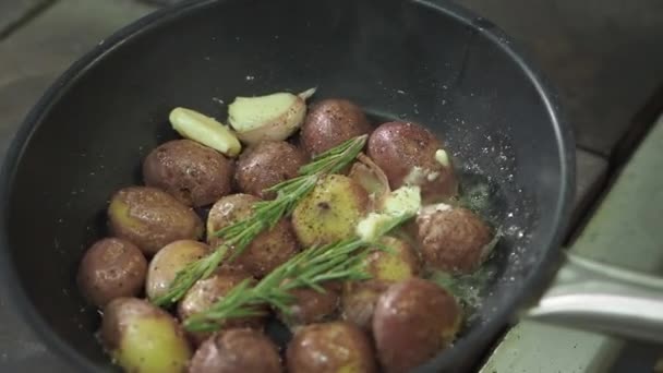 Ein Mann schält mit einem roten Messer eine Kartoffel auf einem schwarzen Granittisch mit vielen anderen Kartoffeln im Hintergrund. Zubereitung von zu kochenden Kartoffeln. — Stockvideo