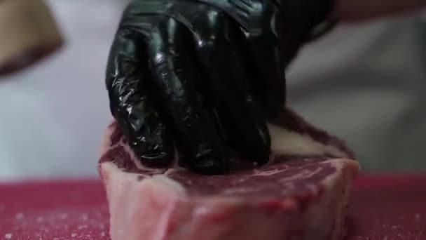 Kocken skär rått kött med kniven. — Stockvideo