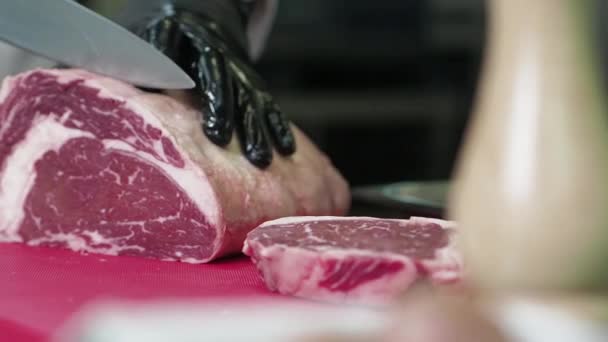 Kocken skär rått kött med kniven. — Stockvideo