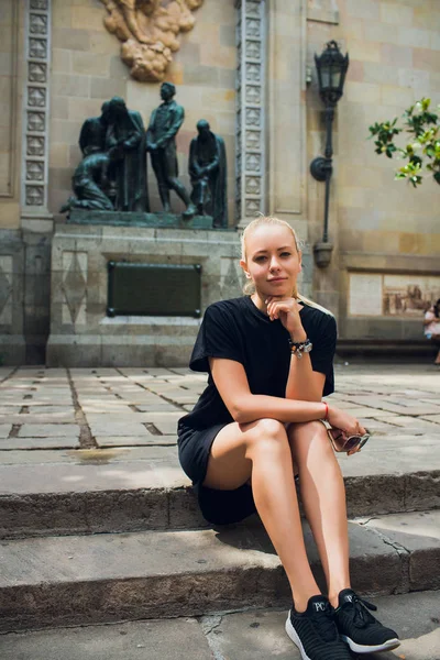 Attrayant fille européenne avec de longs cheveux blonds assis sur les escaliers de l'église dans la vieille ville de Barcelone . — Photo