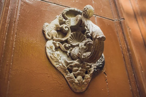 Door handles with an old double door. Golden Handle Door Entrance. Luxury gold handle. classical style golden door handle on brown wood. switches on the wall. Close up of double antique gold plated.