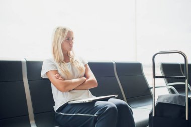 Havaalanı bagaj bavul ve seyahat bekleyen uçuş taşıma rahatlatıcı tatil yaz aylarında için sırt çantası ile oturan terminal dizüstü bilgisayar kullanan kadın.