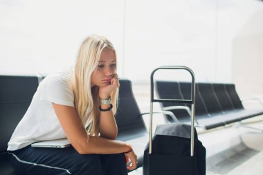 Havaalanı bagaj bavul ve seyahat bekleyen uçuş taşıma rahatlatıcı tatil yaz aylarında için sırt çantası ile oturan terminal dizüstü bilgisayar kullanan kadın.