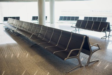 Bavul Havaalanı terminal, bekleme salonunda iki gezgin odaklanmak koltuk, tatil kavramı, arka planda güzel gün batımı.