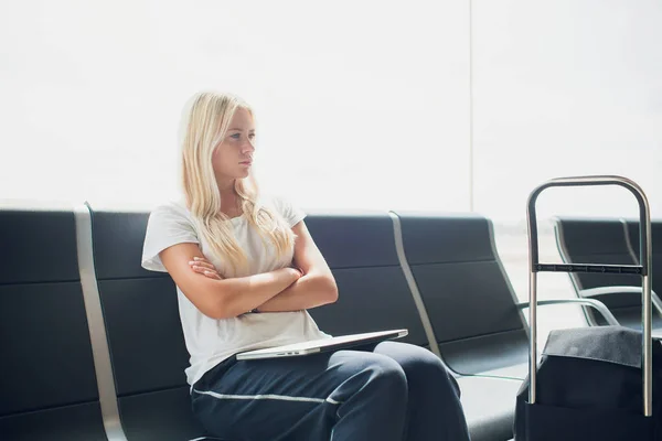 妇女使用笔记本电脑在机场航站楼坐在行李箱和背包旅行在假期暑假放松等待航班运输. — 图库照片