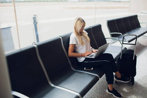 妇女使用笔记本电脑在机场航站楼坐在行李箱和背包旅行在假期暑假放松等待航班运输. — 图库照片