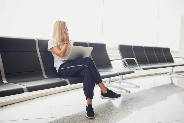 在机场航站楼等飞机的妇女, 坐在椅子上, 在笔记本电脑上打字, 看的一边。顶视图. — 图库照片