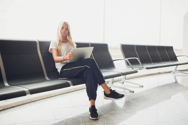 在机场航站楼等飞机的妇女, 坐在椅子上, 在笔记本电脑上打字, 看的一边。顶视图. — 图库照片