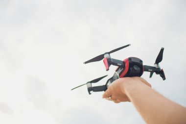 Bir adam, profesyonel bir hava fotoğrafçı quadcopter veya bir video ya da fotoğraf bir yükseklikten bir arazinin almaya gökyüzünde uçak başlattı. Adam bir dron uzaktan kumanda ile çalışma.