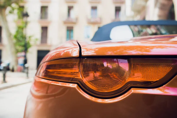 Detail van rode gemetalliseerde oranje achterste auto koplamp in ogen vorm, met zon reflectie in leerling. — Stockfoto