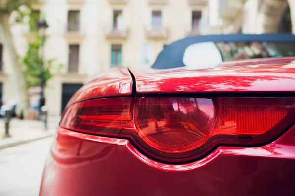 Détail du phare rouge métallisé rouge de voiture arrière en forme d'oeil, avec réflexion du soleil dans la pupille . — Photo