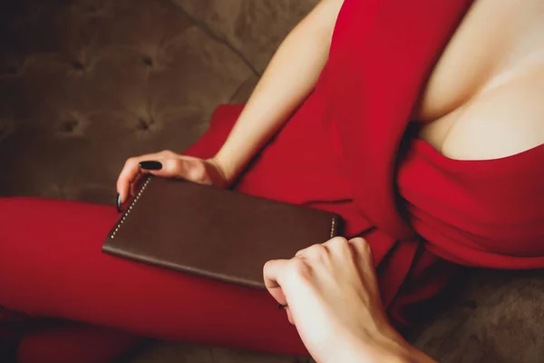 Große Brüste, Schnitt am Kleid, rote Farbe der Kleidung, Frau hält Clutch oder Handtasche. — Stockfoto