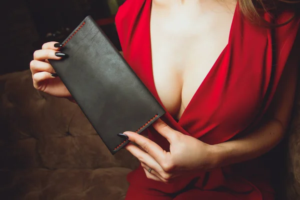 Große Brüste, Schnitt am Kleid, rote Farbe der Kleidung, Frau hält Clutch oder Handtasche. — Stockfoto