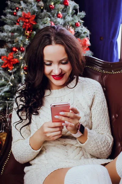 愉快的年轻妇女与礼物盒在圣诞节背景回答电话通过一个聪明的时钟技术概念 — 图库照片