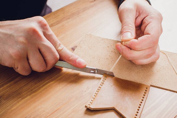 leather craftsman working making products at table in workshop studio.