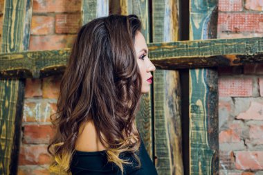 Uzun ve parlak dalgalı saçlı esmer kız. Güzel model kıvırcık saç modeli ile. Baş ve omuzlar.