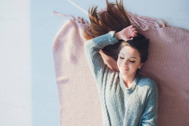 Yatak odasında poz, rahat gri kazak ve örme çorap giyen güzel seksi tan esmer kadın. Dinlen, uyku, konfor kavramı. Genç kadının evde yatakta yatan kapatın. İskandinav ev.