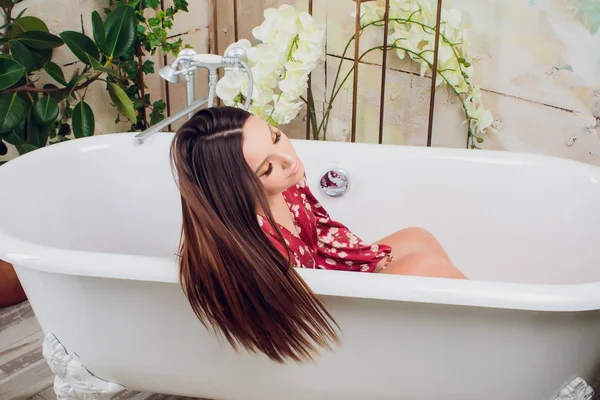Vrouw in wit bad in de badkamer, gezondheid en hygiëne, Wellness en ontspanning, schoonheid en mode, meisje in een rode jurk met make-up — Stockfoto