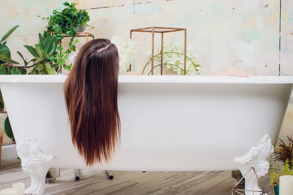 Mulher em banheira branca no banheiro, saúde e higiene, spa e relaxamento, beleza e moda, menina em vestido vermelho com maquiagem — Fotografia de Stock