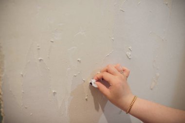 Kadın inşaat işçisi kaldırma duvar kağıdı düz yenileme sırasında çalışır.