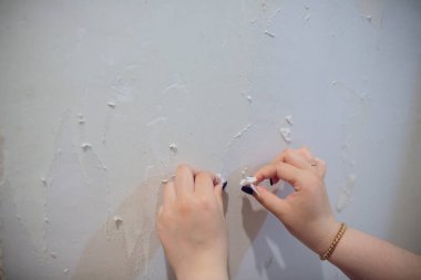Kadın inşaat işçisi kaldırma duvar kağıdı düz yenileme sırasında çalışır.