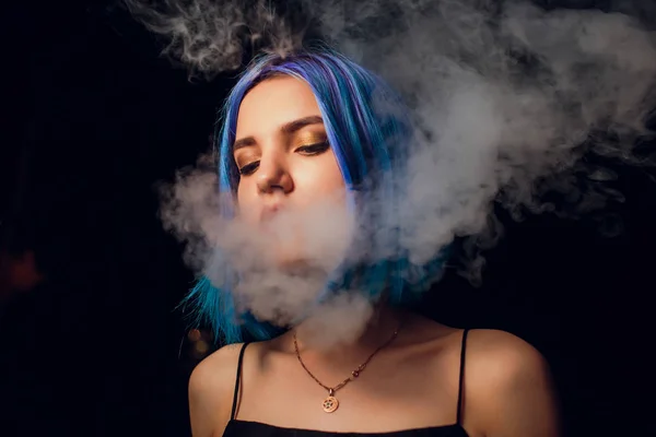 Jovem fumando cigarro eletrônico contra um fundo preto — Fotografia de Stock