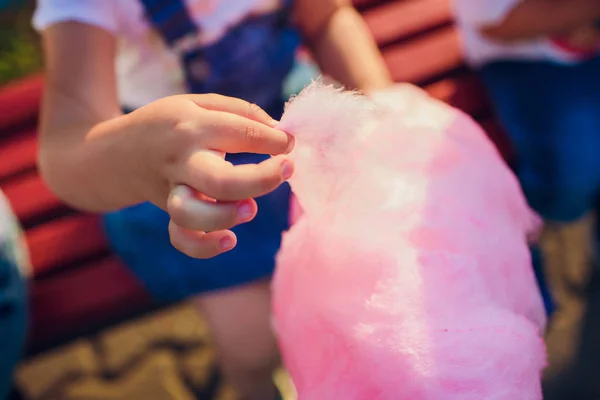 The hands of girl holding pink cotton candy in the background of blue sky — Stock Photo, Image