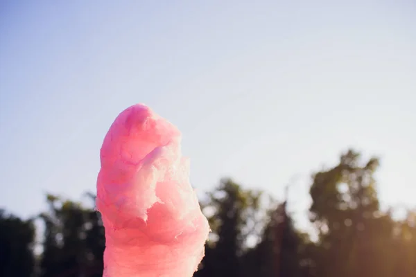 As mãos da menina segurando algodão rosa doce no fundo do céu azul — Fotografia de Stock