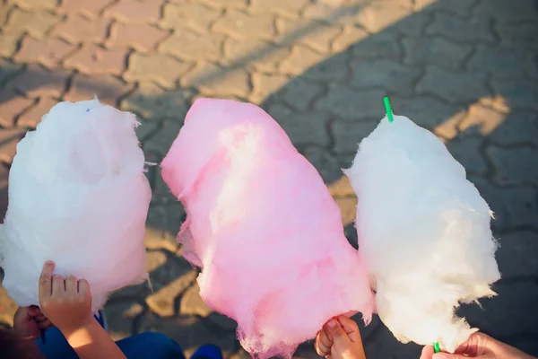 Las manos de la niña sosteniendo algodón rosa de azúcar en el fondo del cielo azul —  Fotos de Stock