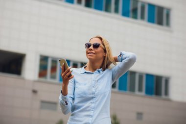 Portre genç işkadını cam duvara yaslanmış iken cep telefonuyla iletişim