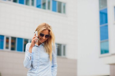 Portre genç işkadını cam duvara yaslanmış iken cep telefonuyla iletişim